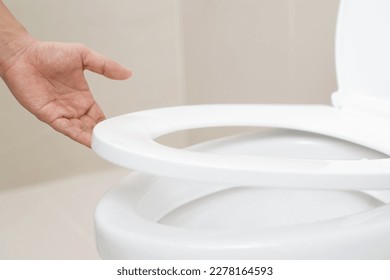 close up hand of a woman closing the lid of a toilet seat. Hygiene and health care concept. - Shutterstock ID 2278164593