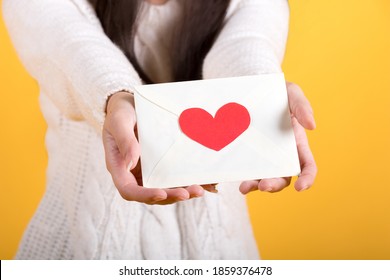 Close Up Of Hand. Woman Holding Valentine's Day Greeting Card. Studio Shot Isolated On Yellow Background.