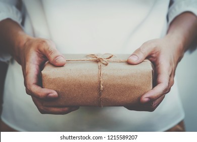 Close Up Hand Woman Present And Holding Kraft Gift Box Packaging.