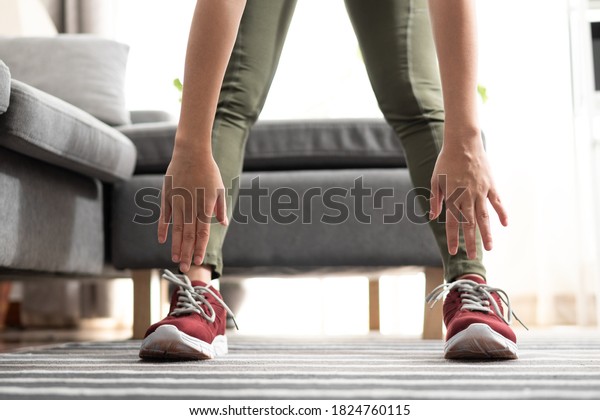Close up hand woman touching\
her toes stretches. Standing forward bend yoga pose stretch at\
home.