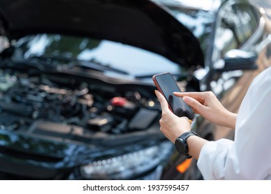 Close up hand of woman using a mobile phone call a car mechanic because car was broken. Contacting car technician or need help concept.