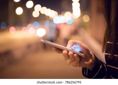 Close Up Hand Of Woman Using Mobile Smartphone In The Street, Night Light Bokeh Background, Copy Space.