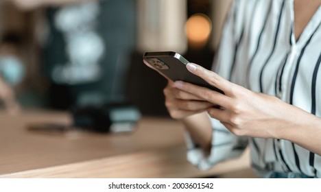 Close up hand of woman using smartphone at coffee shop cafe - Shutterstock ID 2003601542