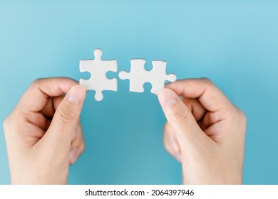 Close up of hand women connecting pieces of a jigsaw puzzle on a blue background, business connection, success, solution, and strategy concept.
