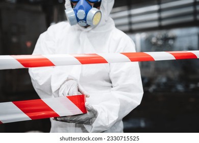 Close up hand of workers wear protection suit checking chemical contaminated oil in old factory. Red and White Lines Marking a Dangerous Zone. Biohazard Contamination Control.