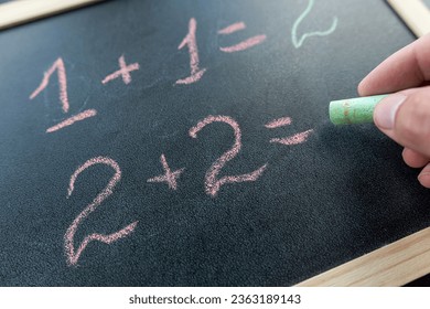 close up hand write primary simple mathematical equation. Math chalkboard , education concept