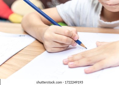 Close Up Hand Writing Homework On Wooden Table At Home. Kid Learing And Writing Alphabet.