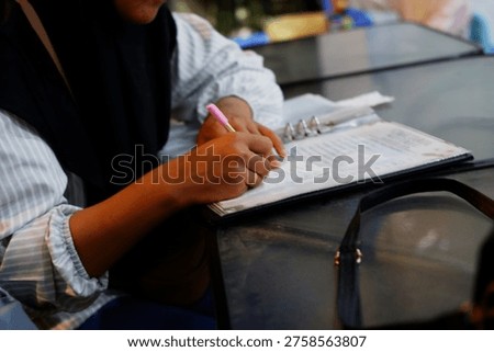 Close Up of Hand Writing Notes on a table