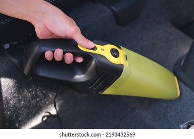 close up hand with yellow vacuum cleaner during washing car salon and textile floor