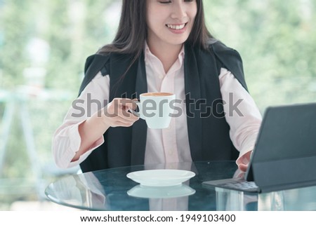 Close up of hand young businesswoman holding coffee cup at workplace during using her digital tablet.