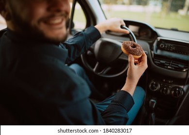 A Close - Up Of Hand Of A Young Caucasian Businessman Holding A Delicious Chocolate Doughnut And Driving A Car On The Way To Work. A Sweet Meal In Transport