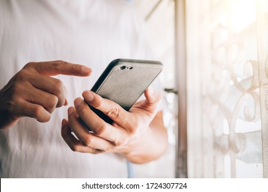 close up the hand of a young man holding a smartphone in his hand and kicking his finger against the screen Working at home shopping online, sending email, man play phone, with copy space for text