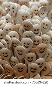 Close up handmade rustic wooden cooking spoons with carved happy smiling face icons in retail market stall display