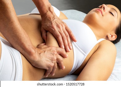 Close up of hands applying pressure with thumbs under woman's thorax. Girl having abdominal physiotherapy in spa.