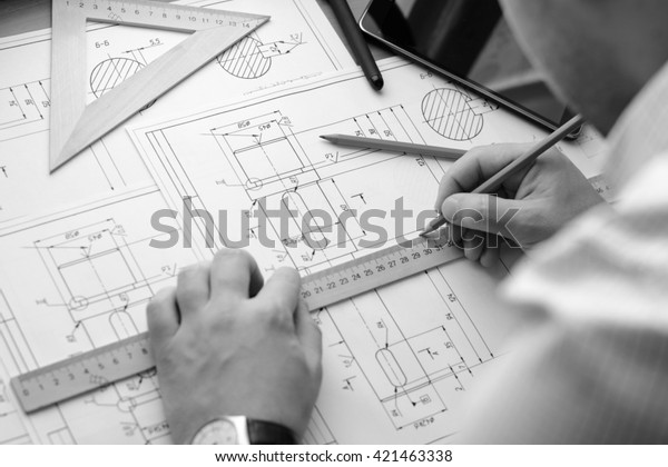Close up of hands of\
architect drawing sketches of construction. He is holding a pencil\
and a ruler
