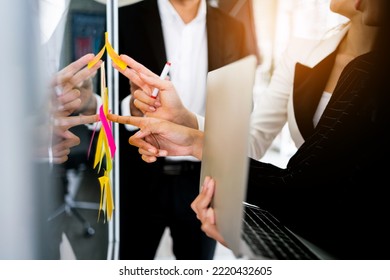 Close up hands of Asian businesswomen. Brainstorm meeting with colorful sticky paper notes on the glass wall for new ideas. Using agile methodology for business in a tech start-up office. - Powered by Shutterstock