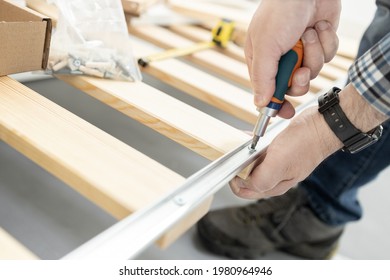 Close Up Of A Hands Assembling A Bed Frame Using A Screwdriver. Furniture Mounting Concept