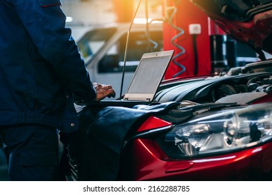 Close up hands of auto electrician using a computer laptop to diagnosing and checking up on car engines parts for fixing and repair - Shutterstock ID 2162288785