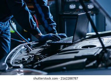 Close up hands of auto electrician using a computer laptop to diagnosing and checking up on car engines parts for fixing and repair - Shutterstock ID 2162288787