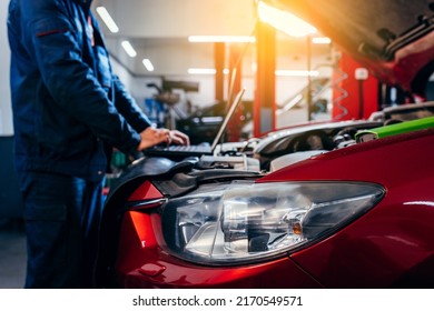 Close up hands of auto electrician using a computer laptop to diagnosing and checking up on car engines parts for fixing and repair - Powered by Shutterstock