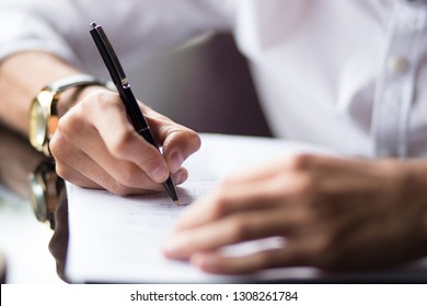 Close Up Of The Hands Of A Businessman In A Shirt Signing Or Writing A Document On A Sheet Of White Paper Using A Nibbed Fountain Pen