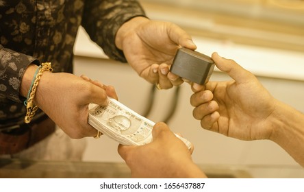 Close Up Of Hands Buying Or Purchasing Gold Jewellery By Paying Indian Currency At Jewelry Shop India - Concept Of Gold Investment For Profit.