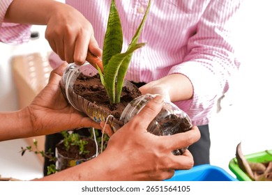 Close Up Of Hands Carefully Adding Soil And Plant To Handmade Recycled Planter