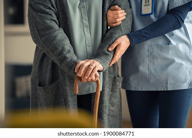 Close up hands of caregiver doctor helping old woman at clinic. Nurse holding a senior patient with walking stick. Elder woman using walking cane at nursing home with nurse holding hand for support.  - Powered by Shutterstock