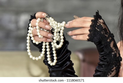 close up of a hands Caucasian retro woman with black vintage gloves holding a necklace of white pearls with her hands on blurry background. Elegant woman
 - Powered by Shutterstock