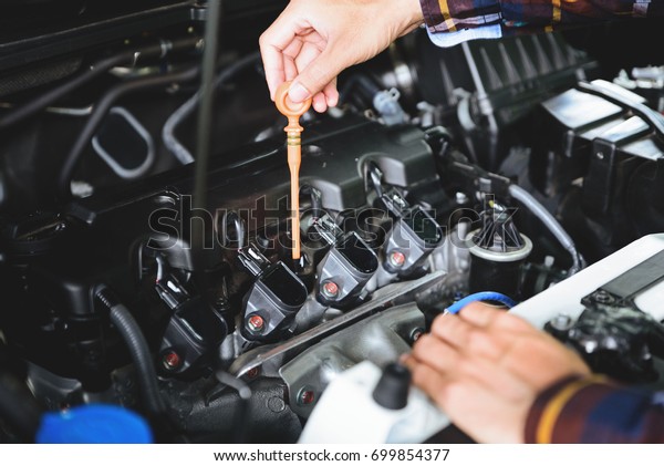 Close up hands checking\
lube oil level of car engine from deep-stick for service and\
maintenance concept.