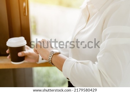 Close up hands checking time on her watch and holding hot coffee cup. Business looking on her wristwatch for waiting someone.