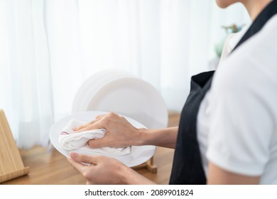Close up hands of cleaning service woman cleaning in kitchen at home. Beautiful young girl housekeeper cleaner feel happy and wipes dishes plates after washing for housekeeping housework or chores.