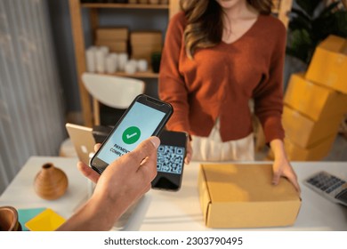 Close up hands of customer using mobile phone paying for goods package. Attractive handsome male customer making a easy and quick contactless payment for product from small business in warehouse store - Powered by Shutterstock