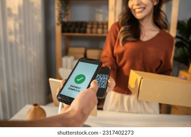 Close up hands of customer using mobile phone paying for goods package. Attractive handsome male customer making a easy and quick contactless payment for product from small business in warehouse store - Powered by Shutterstock