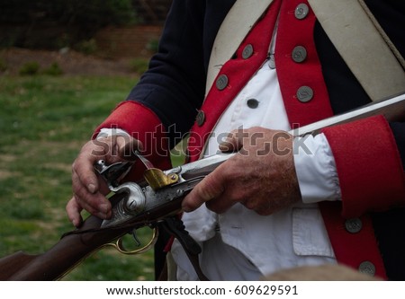 Close up of hands demonstrating how a musket works from a man in Colonial military uniform.