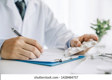Close up hands doctor take pills, tablets and writing prescription.healthcare - Shutterstock ID 1428484757