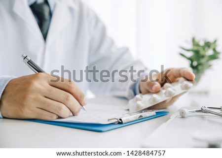 Close up hands doctor take pills, tablets and writing prescription.healthcare