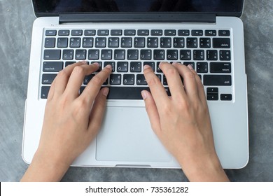 Close up hands of an employee is using a computer notebook by typing on keyboard at the desk. (Intended to focus at the letter on the keyboard)