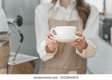 Close up hands of a female barista holding a cup of coffee to serve her customer - Powered by Shutterstock