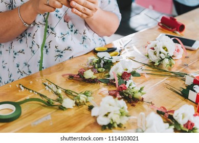Close up of hands of  female caucasian florist as she is working on a groom's wedding boutonniere