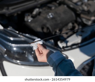 Close up of hands of female driver checking oil level in car engine. 