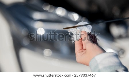 Close up of hands of female driver checking oil level in car engine. 