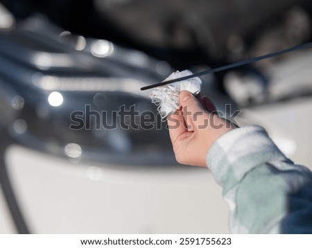 Close up of hands of female driver checking oil level in car engine. 