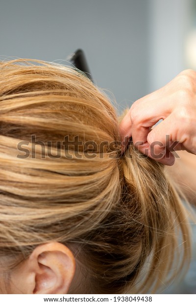 Close up of hands of female hairdresser
styling hair of a blonde woman in a hair
salon