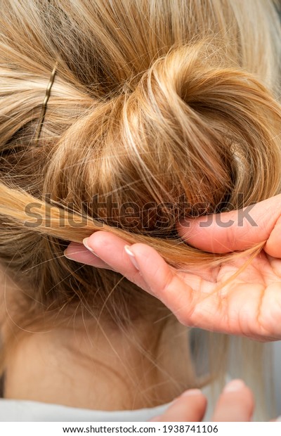 Close up of hands of female hairdresser\
styling hair of a blonde woman in a hair\
salon