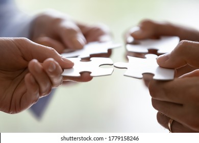 Close up hands of four businesspeople hold pieces of white puzzle, assemble jigsaw, put it together, joint path to problem solution, find way out exit of difficult situation. Support, teamwork concept - Shutterstock ID 1779158246