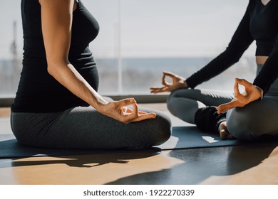 Close Up Hands. Girl Do Yoga Indoors. Pregnant Women Exercising Yoga At Sunrise With A Warmth Background In Gym. Meditation Prenatal Class On Fitness Center.