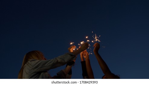 close up of hands of girls holding sparklers . Group of friends celebrating waving sparkler fireworks dancing enjoying party having fun holiday celebration at evening social gathering on rooftop - Powered by Shutterstock