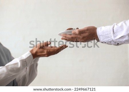 Close up hands giving dates fruit and other hand accept it on white background. Iftar and ramadan kareem concept. 