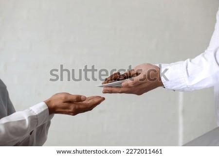 Close up hands giving dates fruit and other hand accept it on white background. Iftar and ramadan kareem concept.